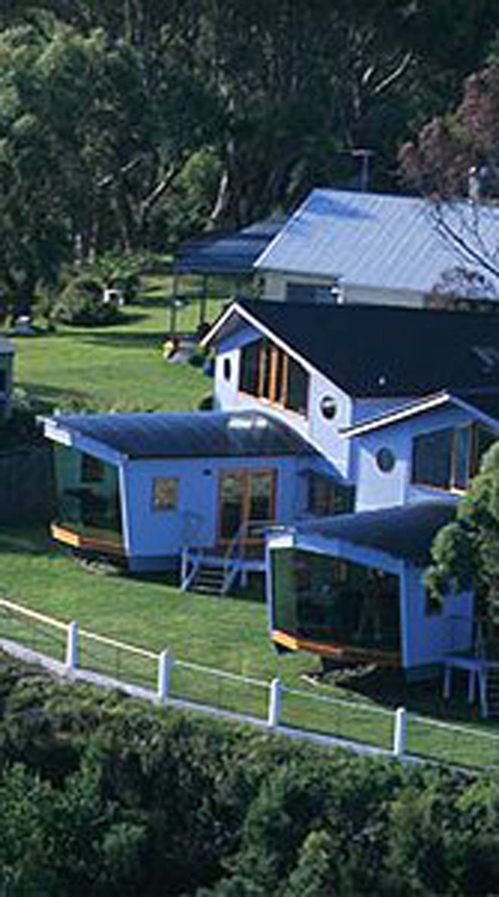 A house with a blue exterior, a large deck, and a fenced yard.