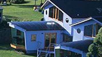 A house with a blue exterior, a large deck, and a fenced yard.