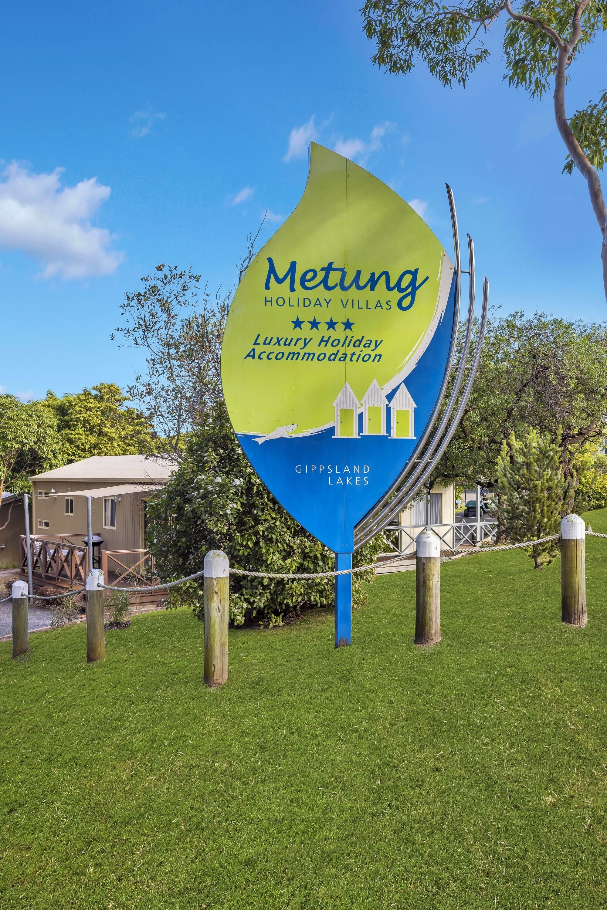 Een bordje voor Metung Holiday Villas in Gippsland Lakes, met een logo met een huis en een meer.