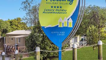 Een bordje voor Metung Holiday Villas in Gippsland Lakes, met een logo met een huis en een meer.