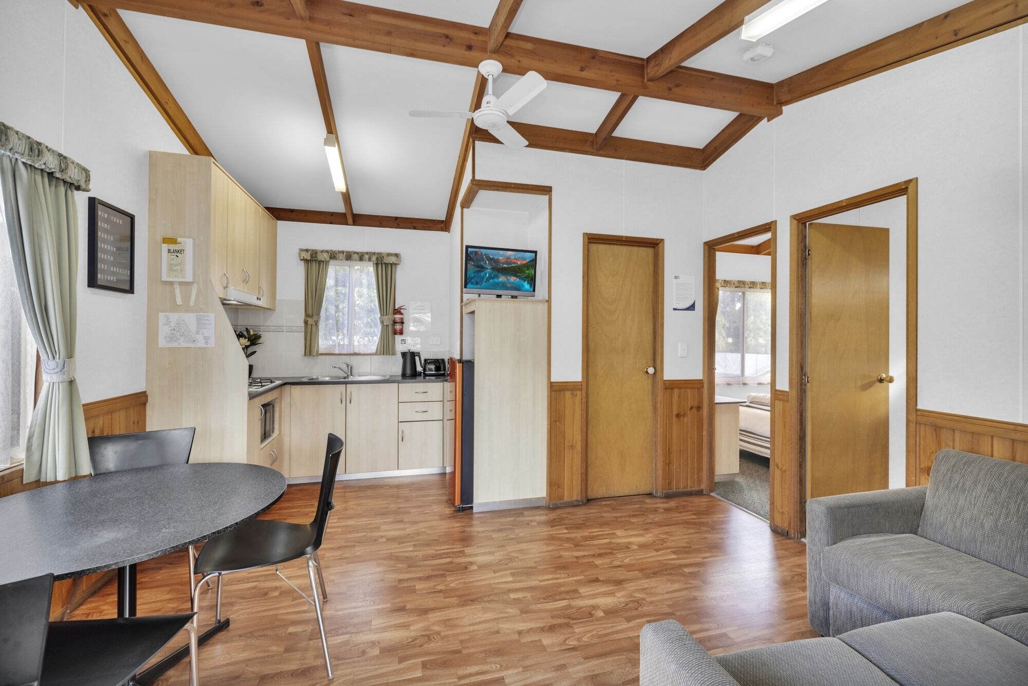 Un vaste espace de vie comprenant une table à manger et des chaises, une cuisine avec des meubles en bois et un coin salon confortable avec un canapé.