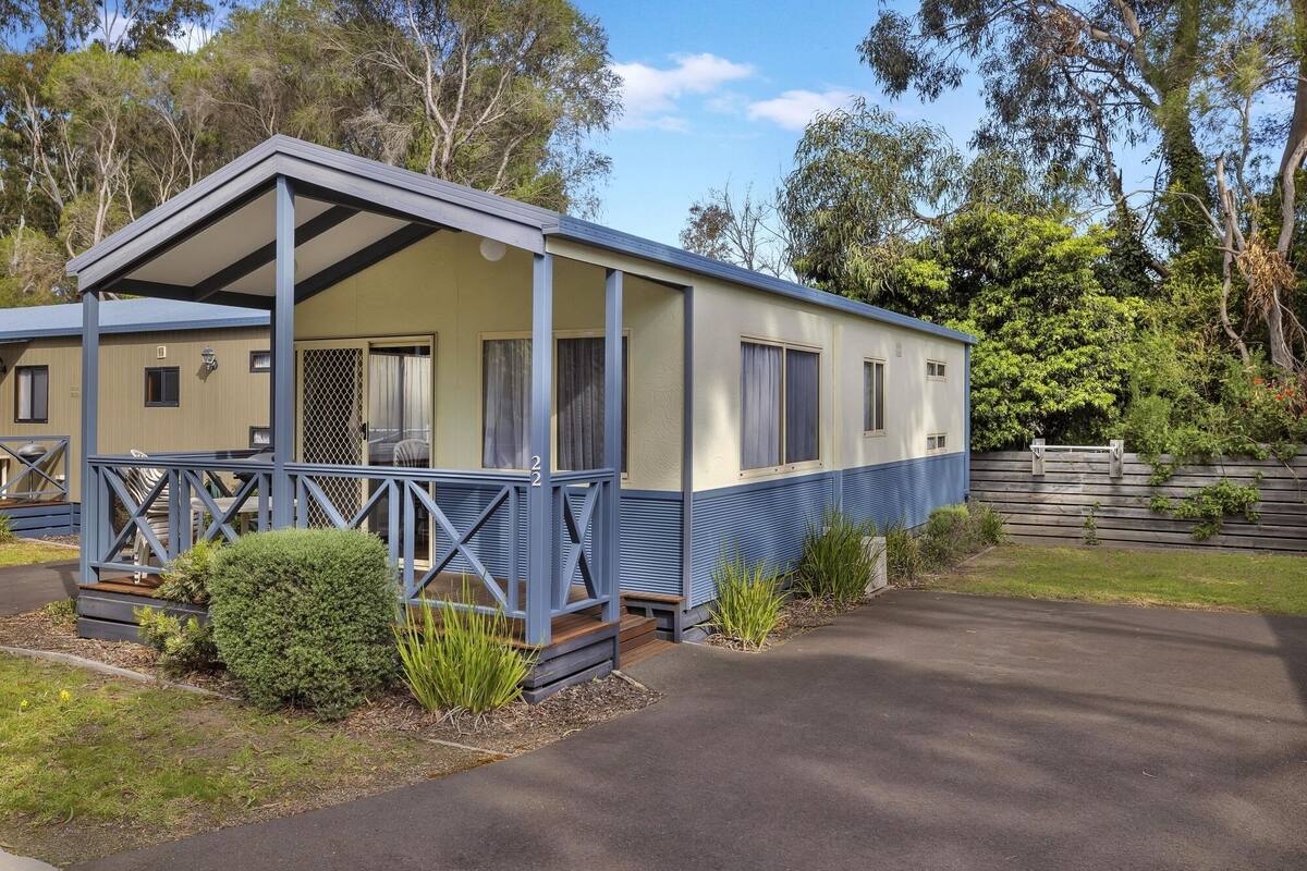 Une maison mobile dotée d’un porche, d’une petite terrasse et d’une cour clôturée.