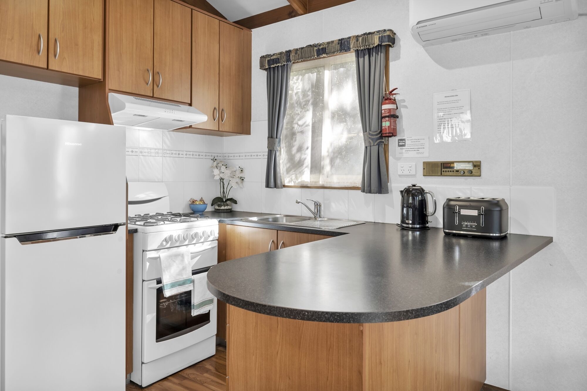 A kitchen with wooden cabinets, a white refrigerator, a stove, a sink, and a toaster.