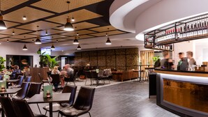 Een modern restaurant met een bar, zitplaatsen en een decoratief plafond.