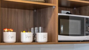 Een keuken met een magnetron, broodrooster en koffiezetapparaat op het aanrecht.