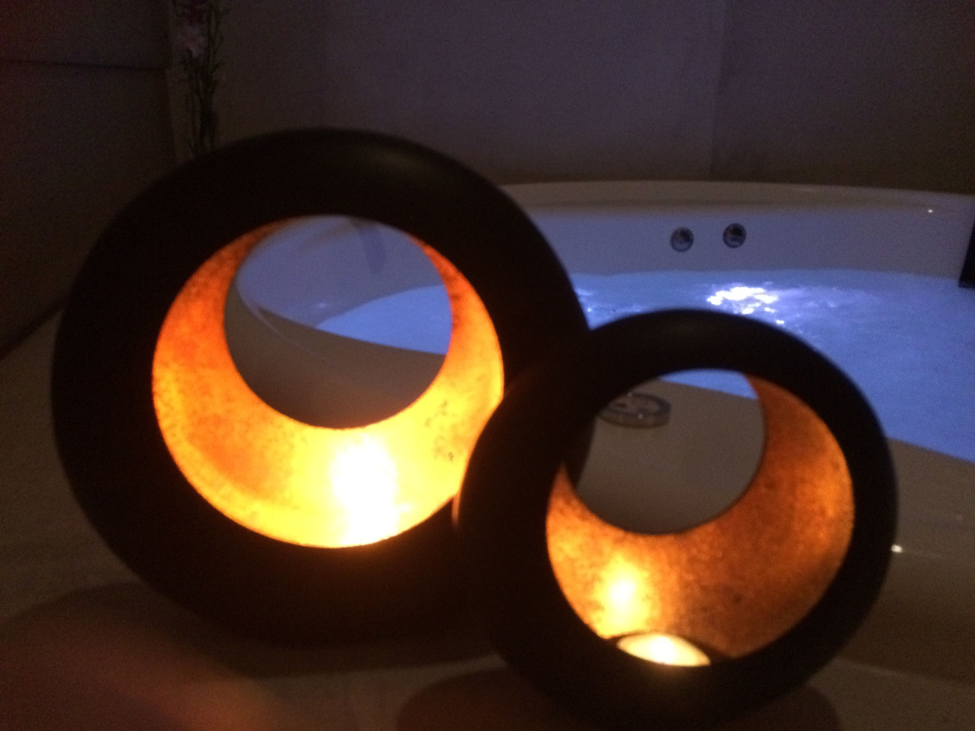 Two illuminated rings on a table with a hot tub in the background.
