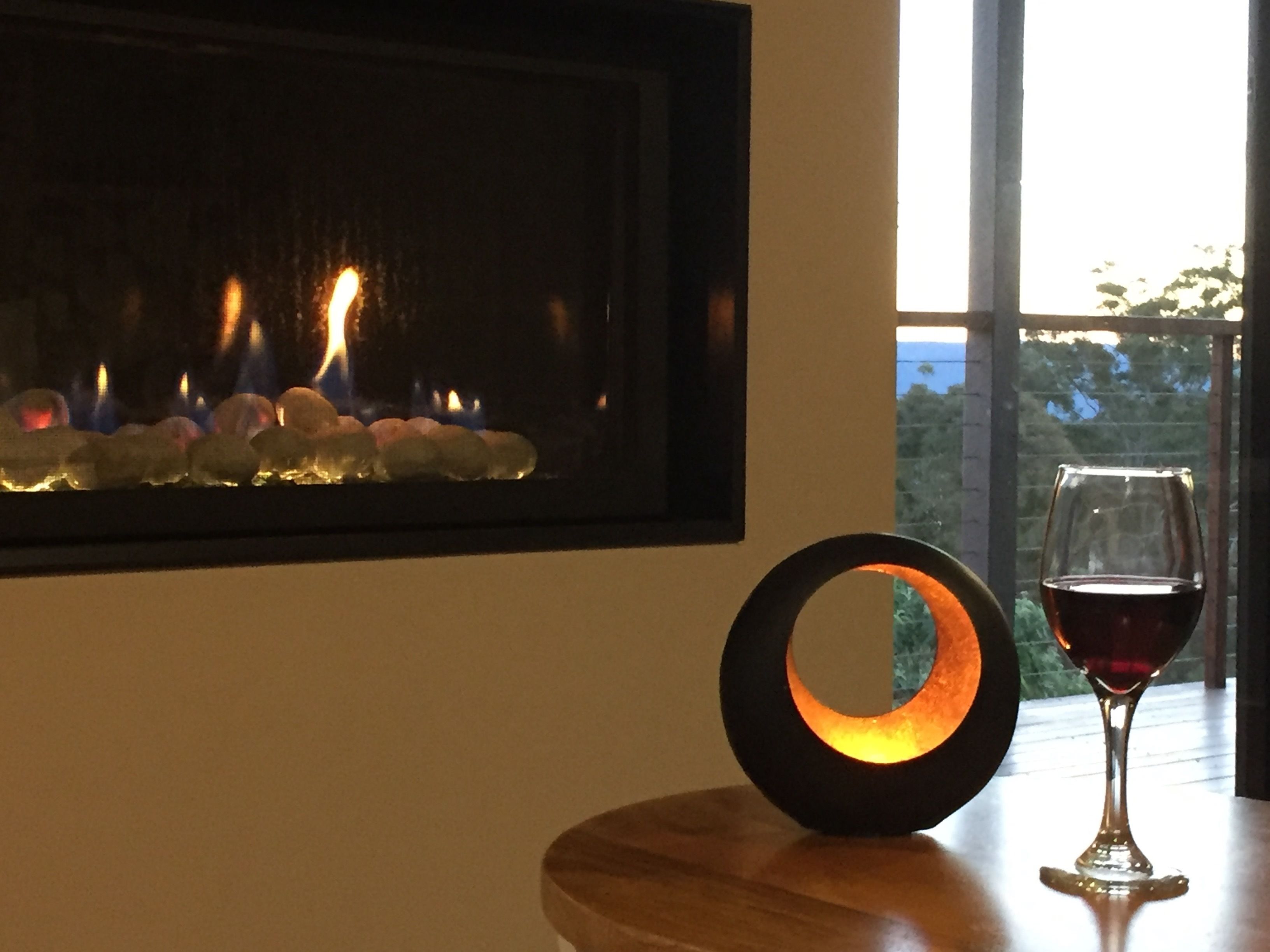 A fireplace with a glass door, a wine glass, and a circular object on a table.