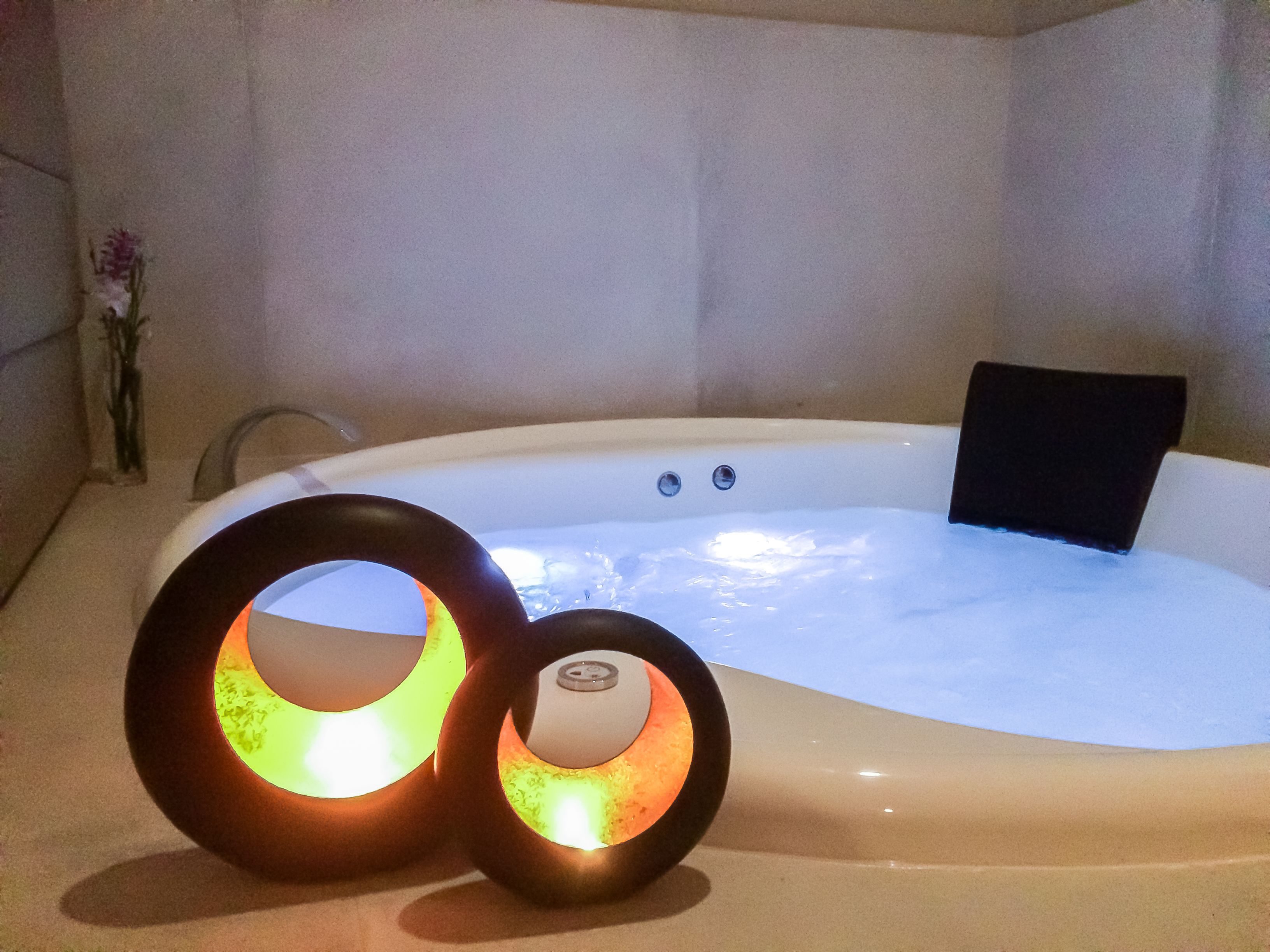 A hot tub with two circular light fixtures and a black cushion.