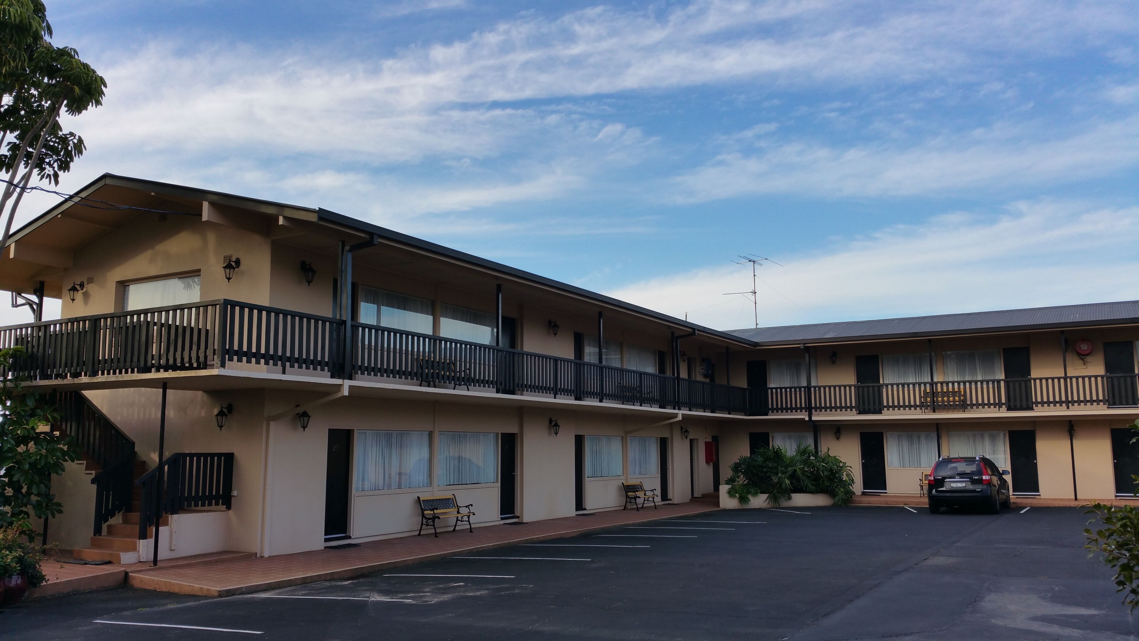 En motel med to etager og en parkeringsplads foran.