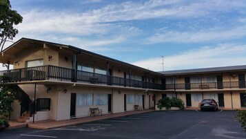 Un motel de dos pisos con estacionamiento al frente.