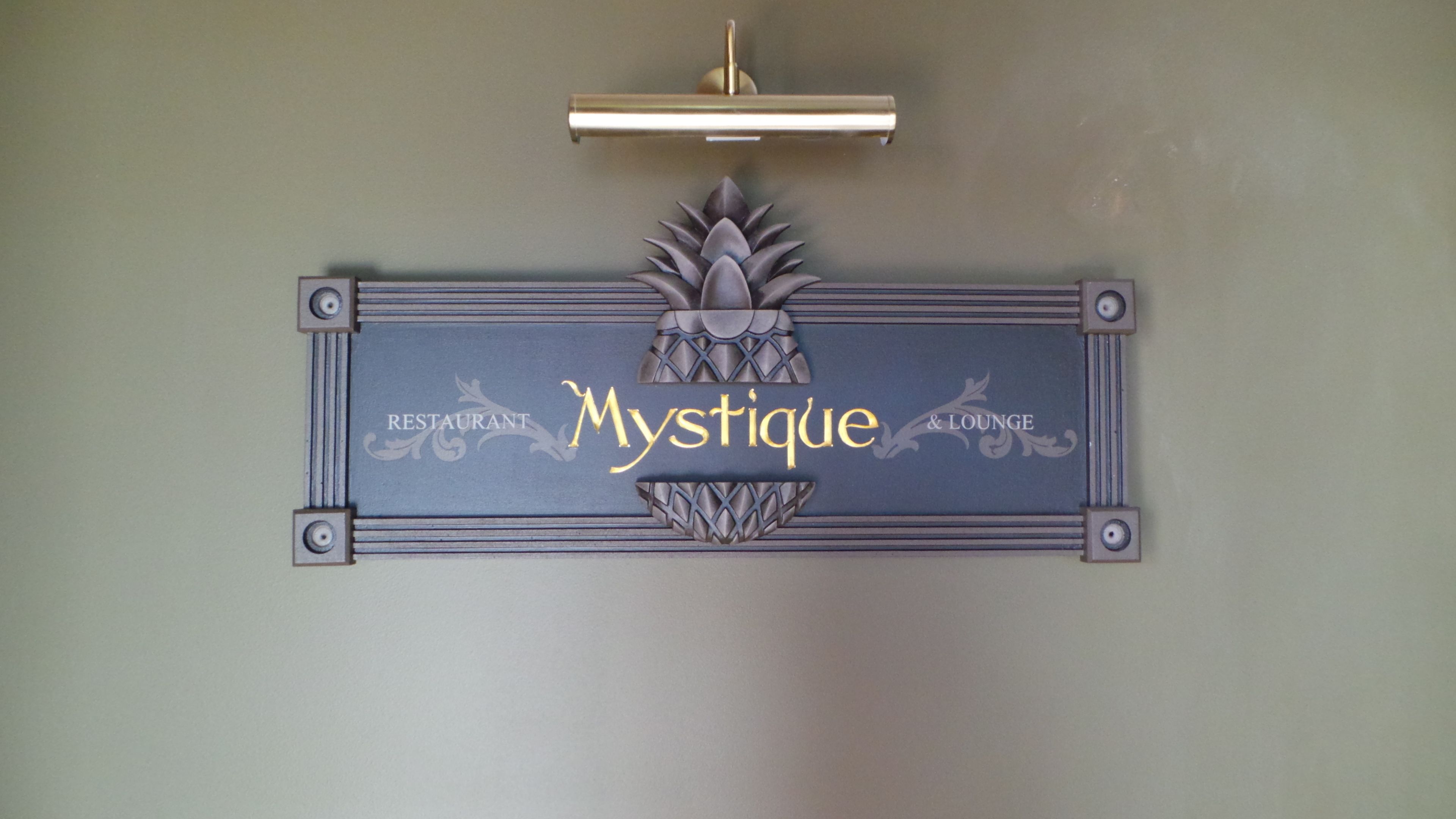 A wall-mounted sign with the name "Mystique" and the words "RESTAURANT & LOUNGE" indicating the establishment's name and function.