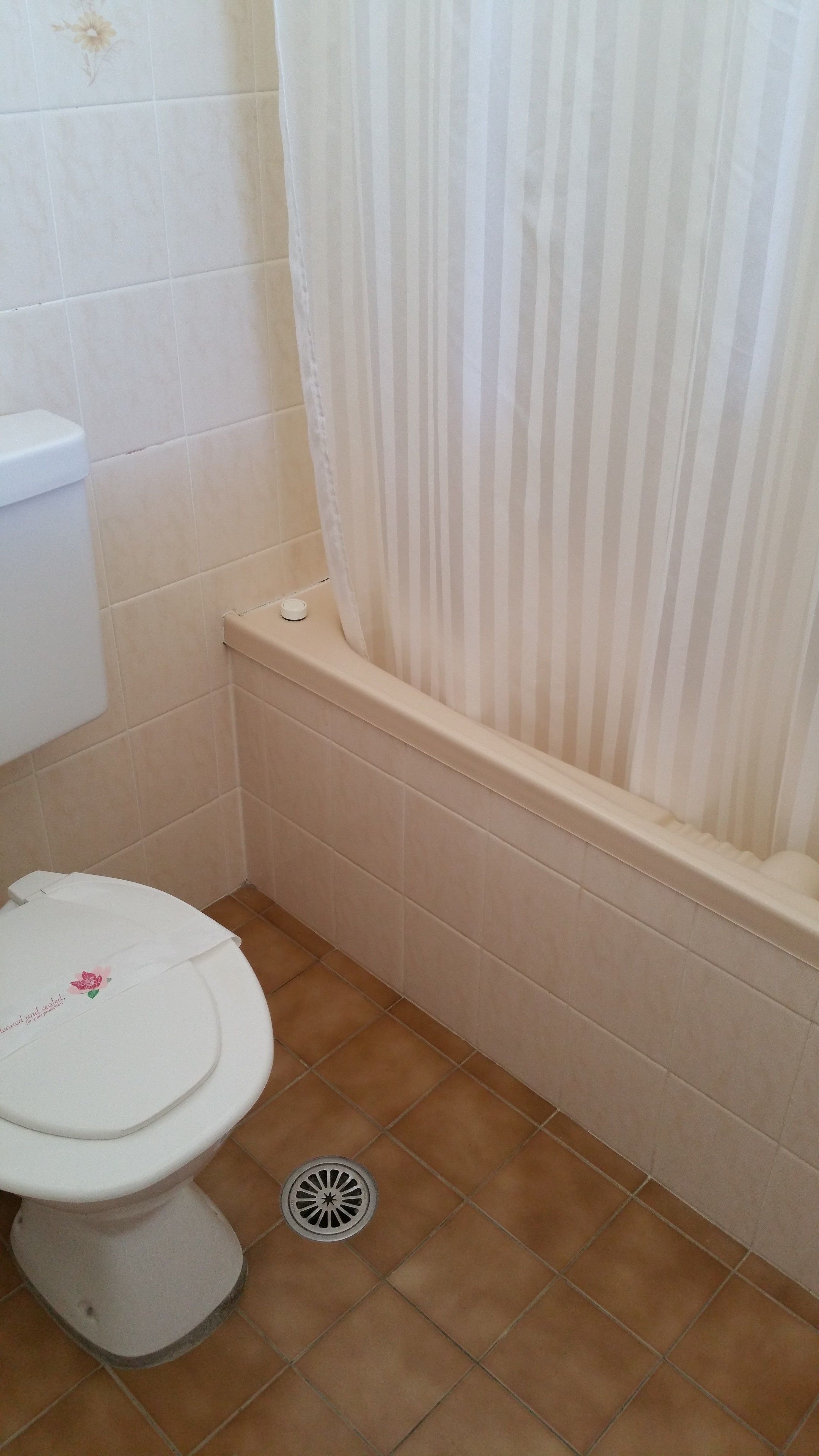 A bathroom with a toilet, a bathtub, and a shower curtain.