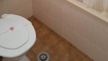 A bathroom with a toilet, a bathtub, and a shower curtain.