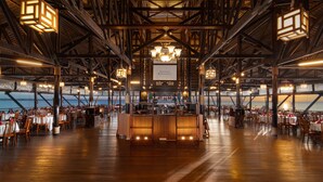 A spacious restaurant with wooden beams and a high ceiling, featuring a central bar area and tables arranged for dining. - Banyu Biru Villa (Bintan)