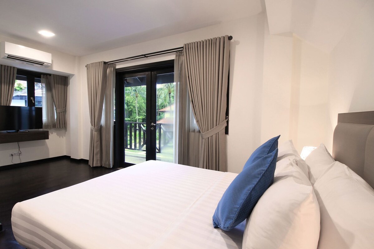 A hotel room with a bed, curtains, a TV, and a balcony with a view.