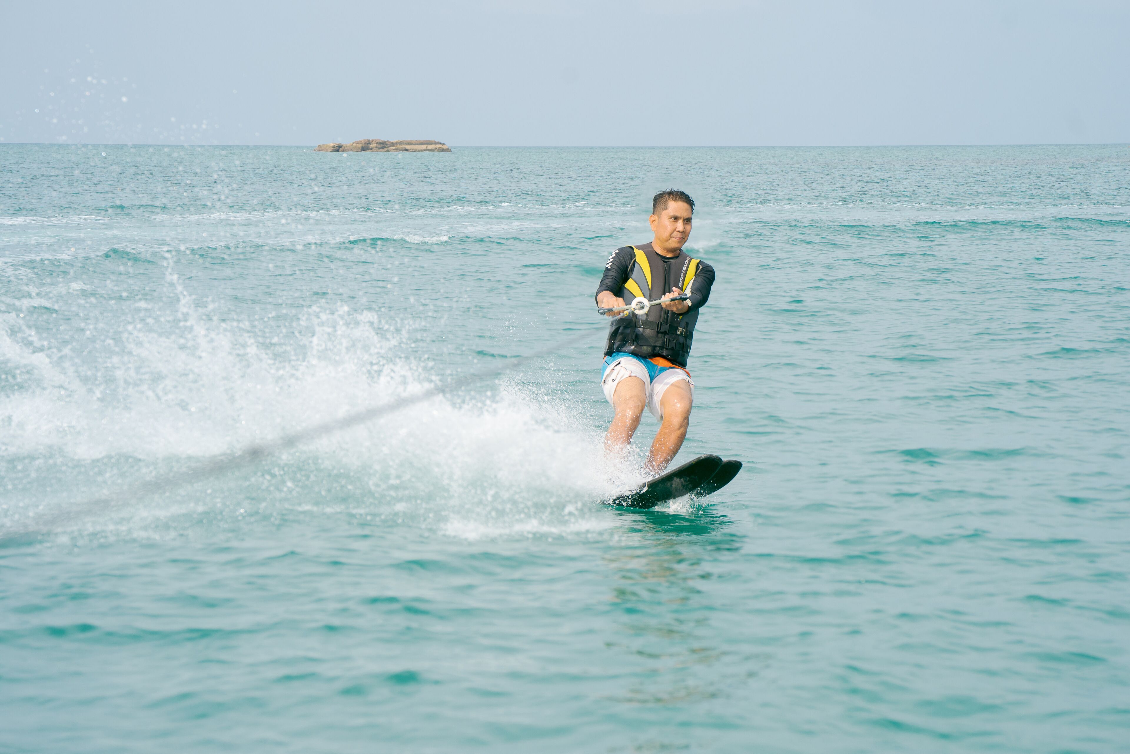 A person wakeboarding on a body of water with a distant island in the background.