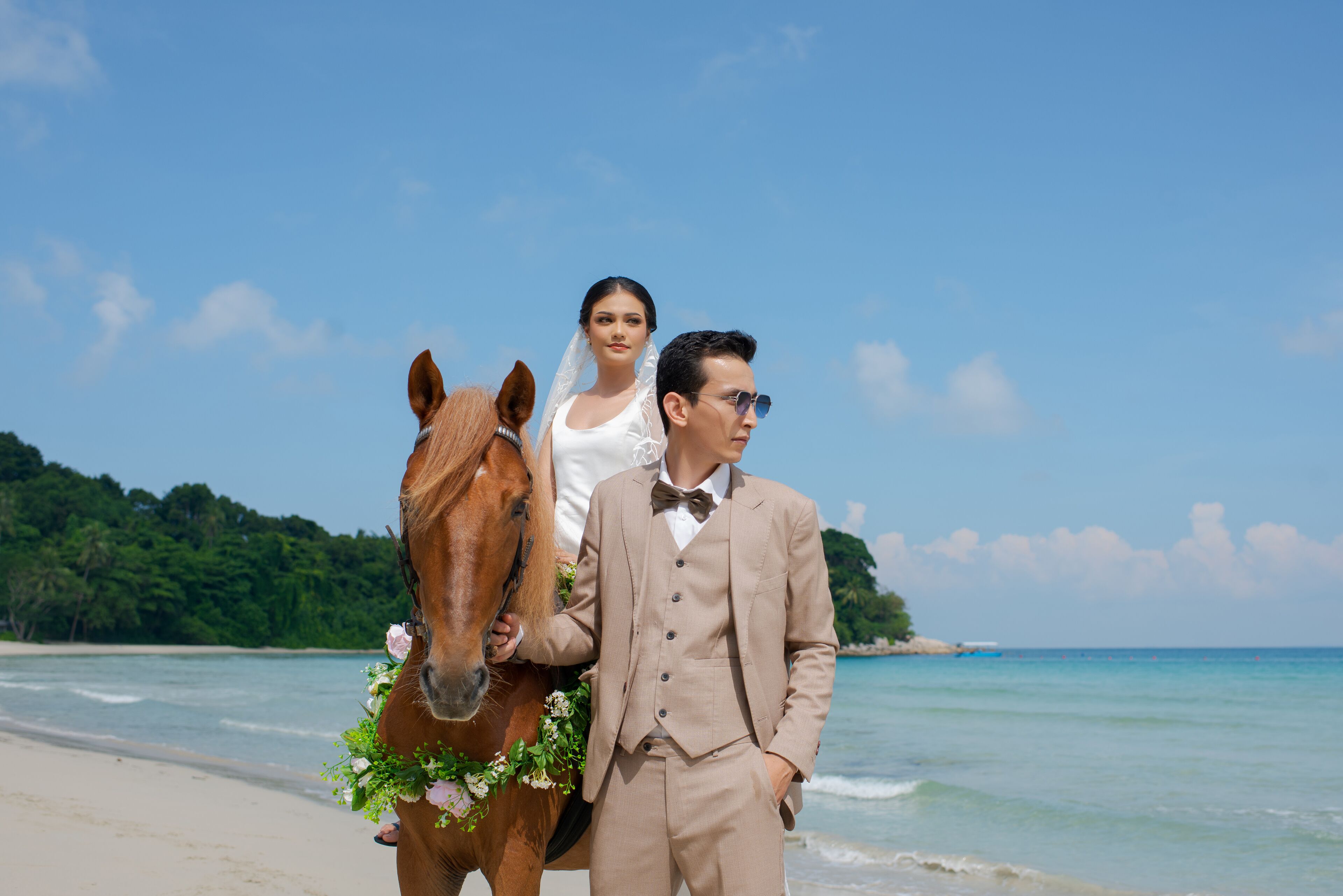 A beach with a horse and a person in a suit.