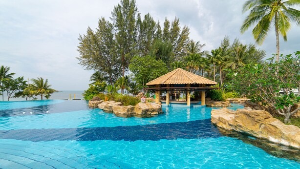 A clear blue pool with a gazebo and palm trees. - Banyu Biru Villa (Bintan)