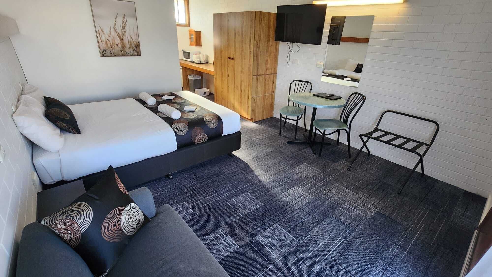 A compact room with a bed, a small table, and two chairs.