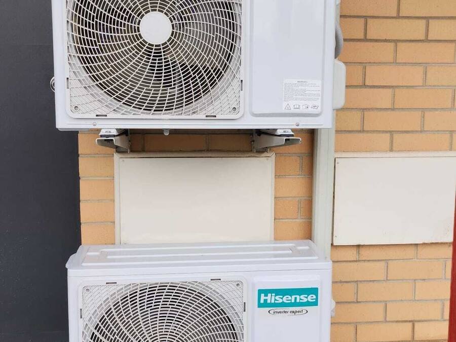 Dois aparelhos de ar condicionado Hisense inverter, modelo Expert, fixados em parede de tijolos.