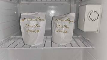 Ein sauberer, leerer Kühlschrank mit zwei Tüten mit dem Aufdruck 'Saubere Gläser' an den Türablagen.
