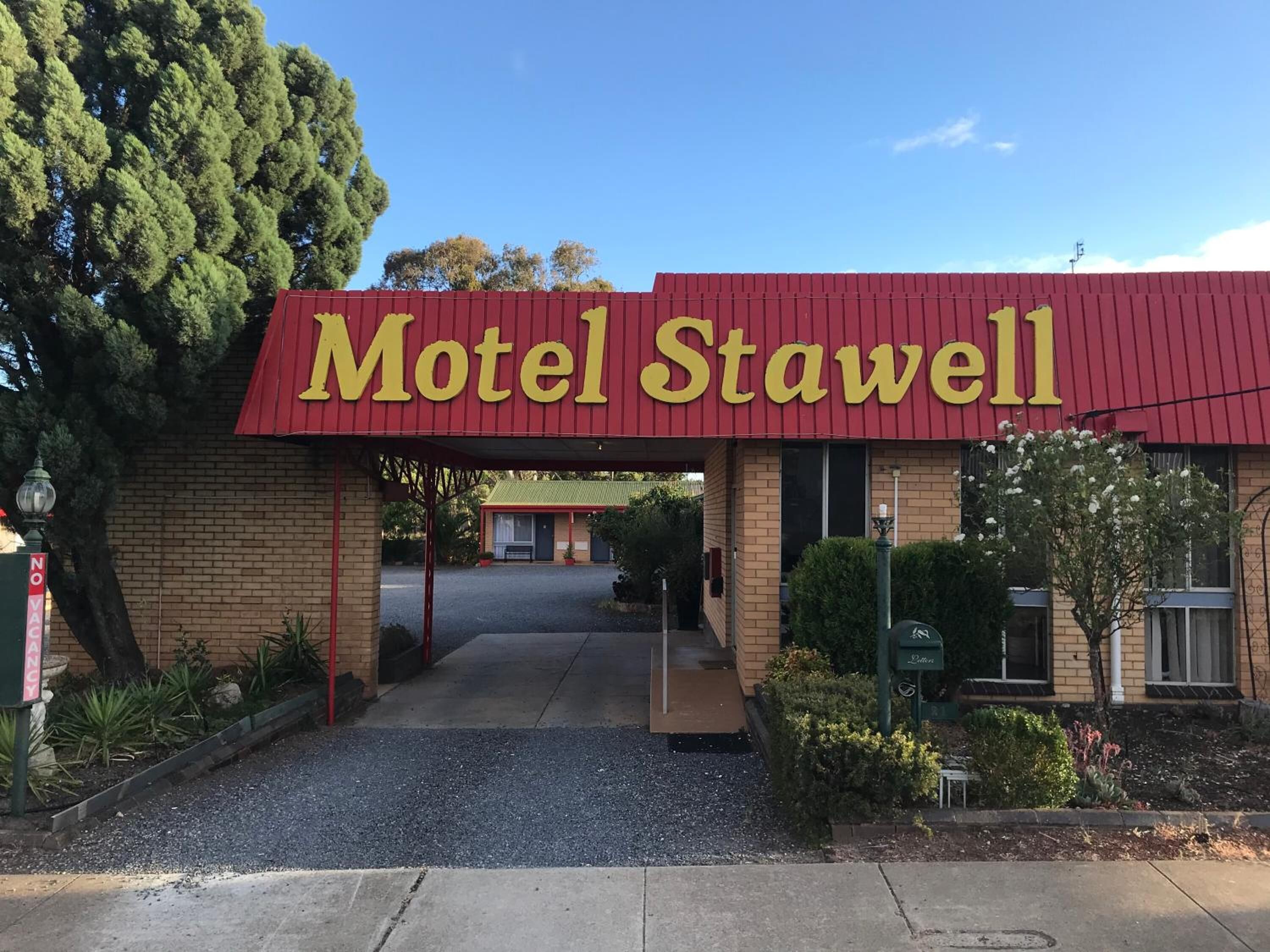 The entrance to Motel Stawell with a red awning and a clear view of the parking area.
