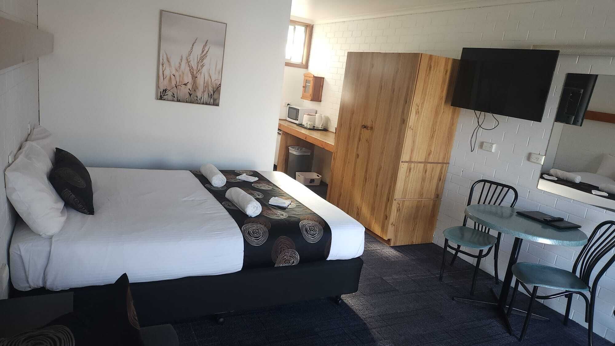 Una habitación de hotel con una cama, un escritorio, una silla, un televisor y un armario de madera.
