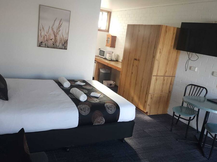 Una habitación de hotel con una cama, un escritorio, una silla, un televisor y un armario de madera.