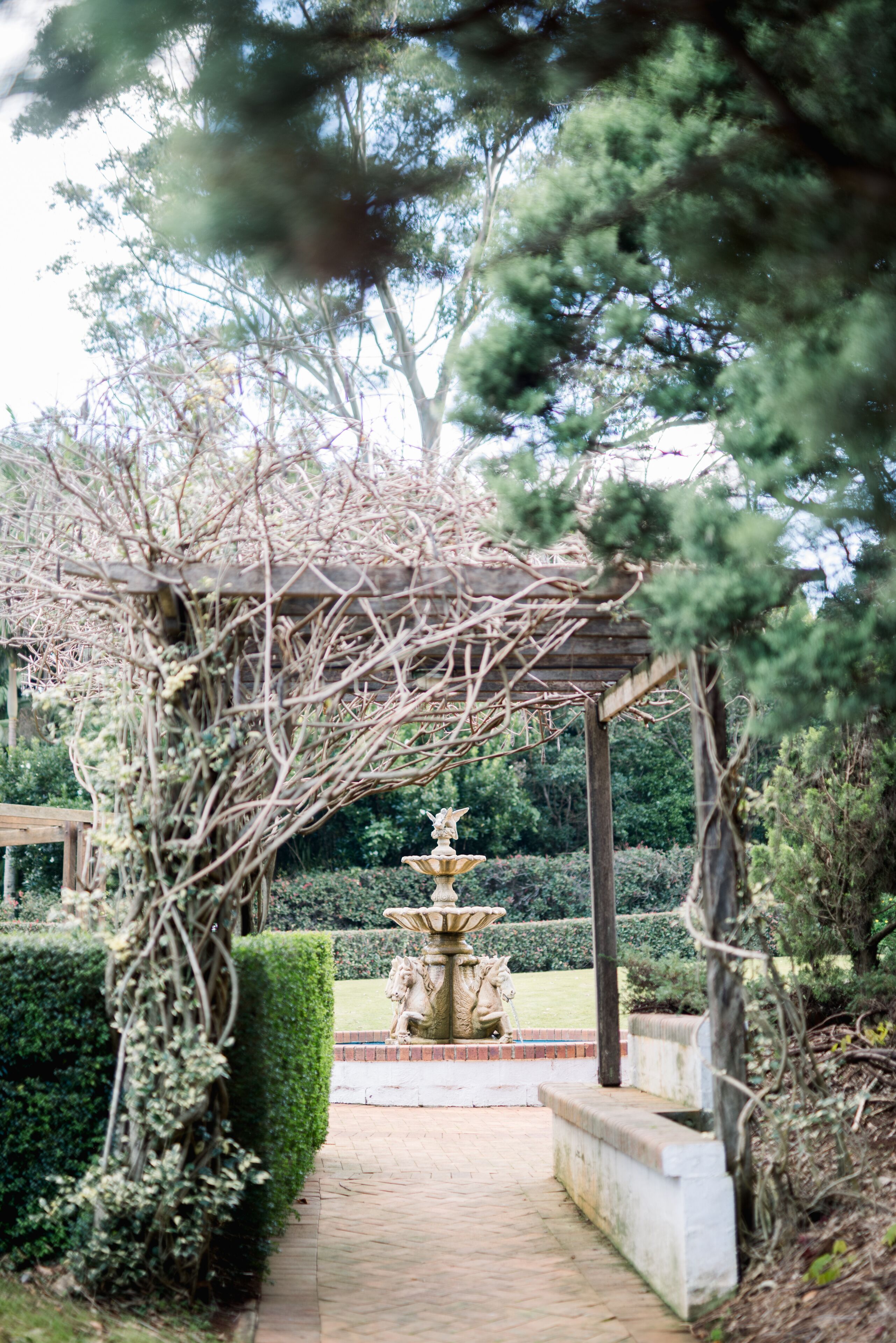 A garden pathway leading to a gazebo with a stone fountain.