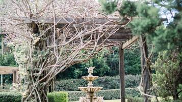 A garden pathway leading to a gazebo with a stone fountain.