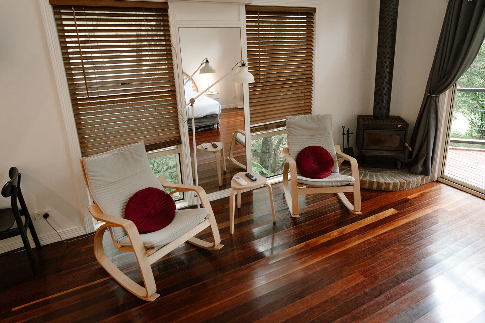 A room with two rocking chairs, a fireplace, and a large window with blinds.