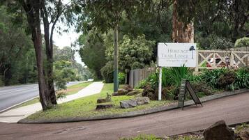 A sign for Heritage Trail Lodge with a view of a road and trees.