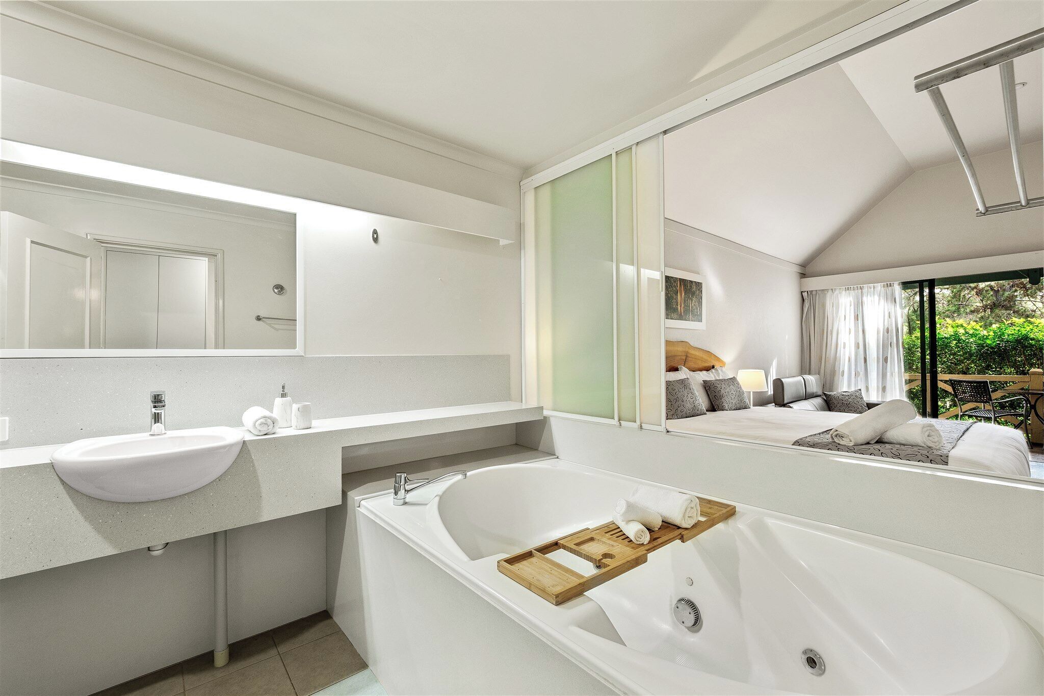 Ein modernes Badezimmer mit einer großen weißen Badewanne, einem Waschbecken und einem Spiegel.