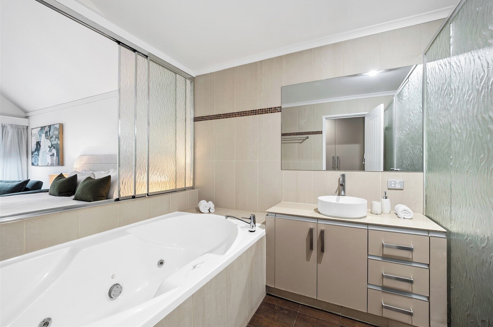 A modern bathroom with a large bathtub, a sink, and a mirror.