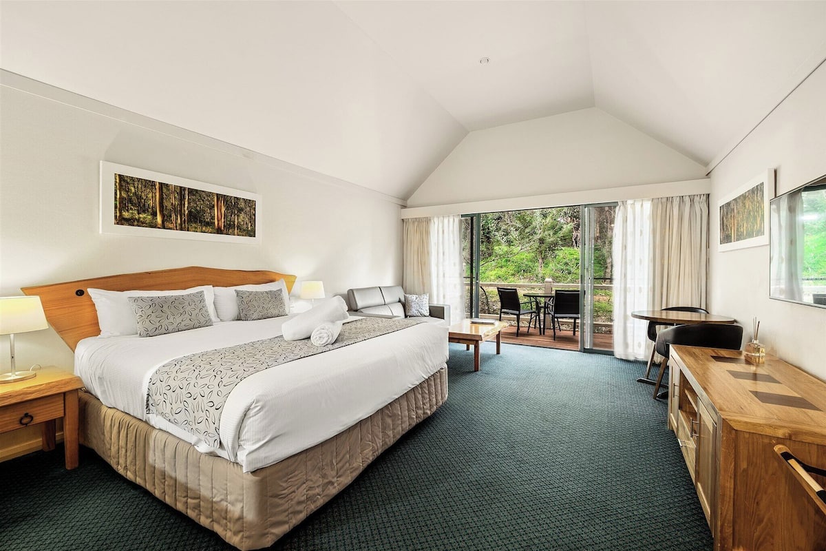 A hotel room with a large bed, a desk, and a view of the outdoors.