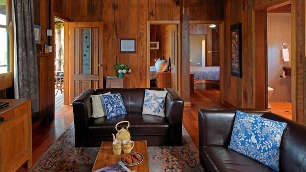 Un salon au plancher de bois, avec un canapé, une table basse et un ventilateur de plafond.