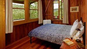 Une pièce en bois avec un lit, un ventilateur de plafond et de grandes fenêtres.