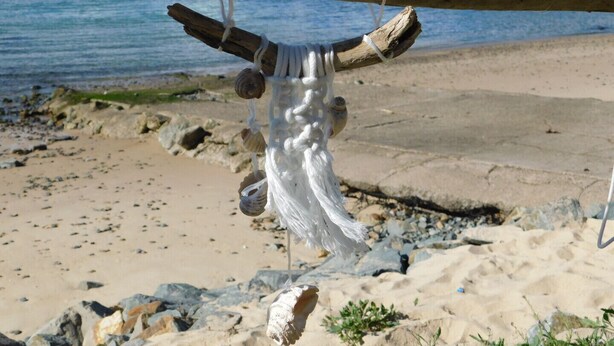 A wooden structure with shells and ropes, located on a rocky beach with a view of the sea. - Beachport Bed and Breakfast (Port Macquarie)