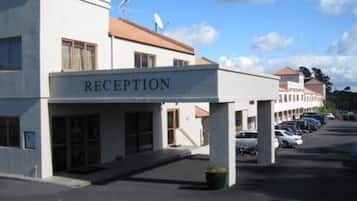 A building with a reception area, a parking lot, and a clear sky.
