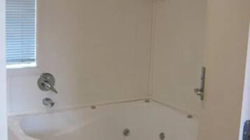 A bathroom with a bathtub, a window, and a shower area.