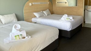 A hotel room with two beds, a wooden headboard, a large mirror, and a bathroom with a sink and mirror. - Shamrock Hotel Motel (Toowoomba)