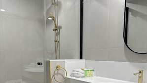 A modern bathroom with a glass-enclosed shower, a white sink with gold fixtures, and a large mirror. - Shamrock Hotel Motel (Toowoomba)
