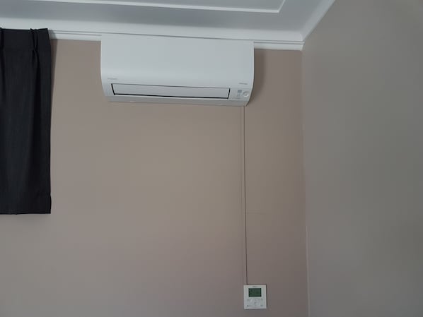 A room with a white ceiling-mounted air conditioner and a wall-mounted thermostat. - Gateshead Tavern Motel (Gateshead)