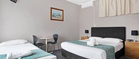 A hotel room with two beds, a desk, a chair, a TV, and a painting on the wall.