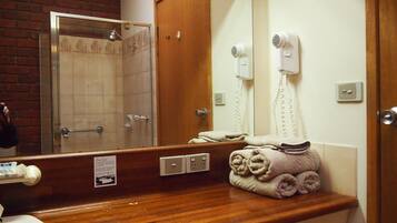 A bathroom with a shower, a hairdryer, a towel rack, and a mirror.