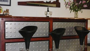 A reception area with a polished metal counter, black funnel-shaped stools, and a decorative wall with a nameplate. - Murray River Motel (Swan Hill)