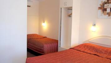 A room with two beds, a wardrobe, and a wall-mounted artwork.
