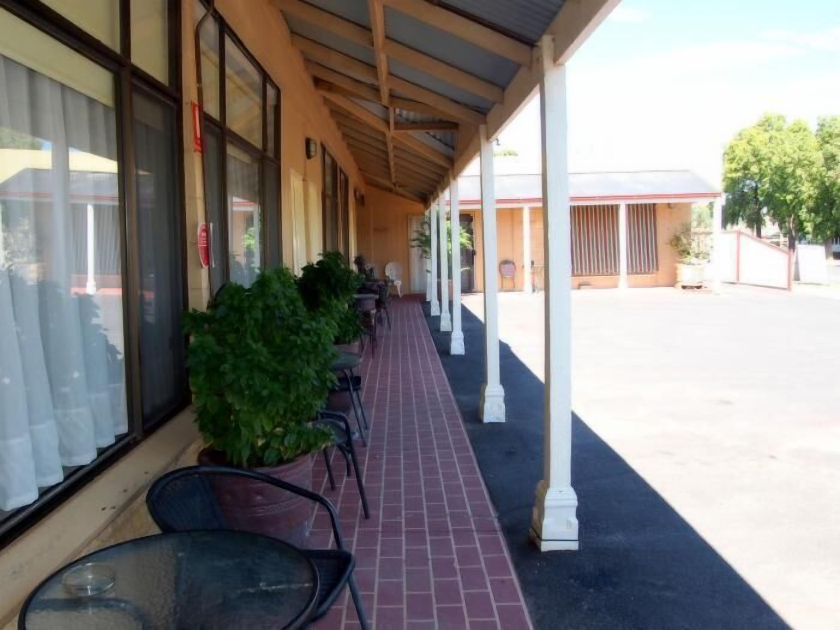 A covered outdoor seating area with potted plants and tables.