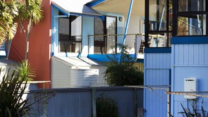 Un edificio residenziale con facciata blu e bianca, un portone del garage visibile e una recinzione in legno in primo piano.