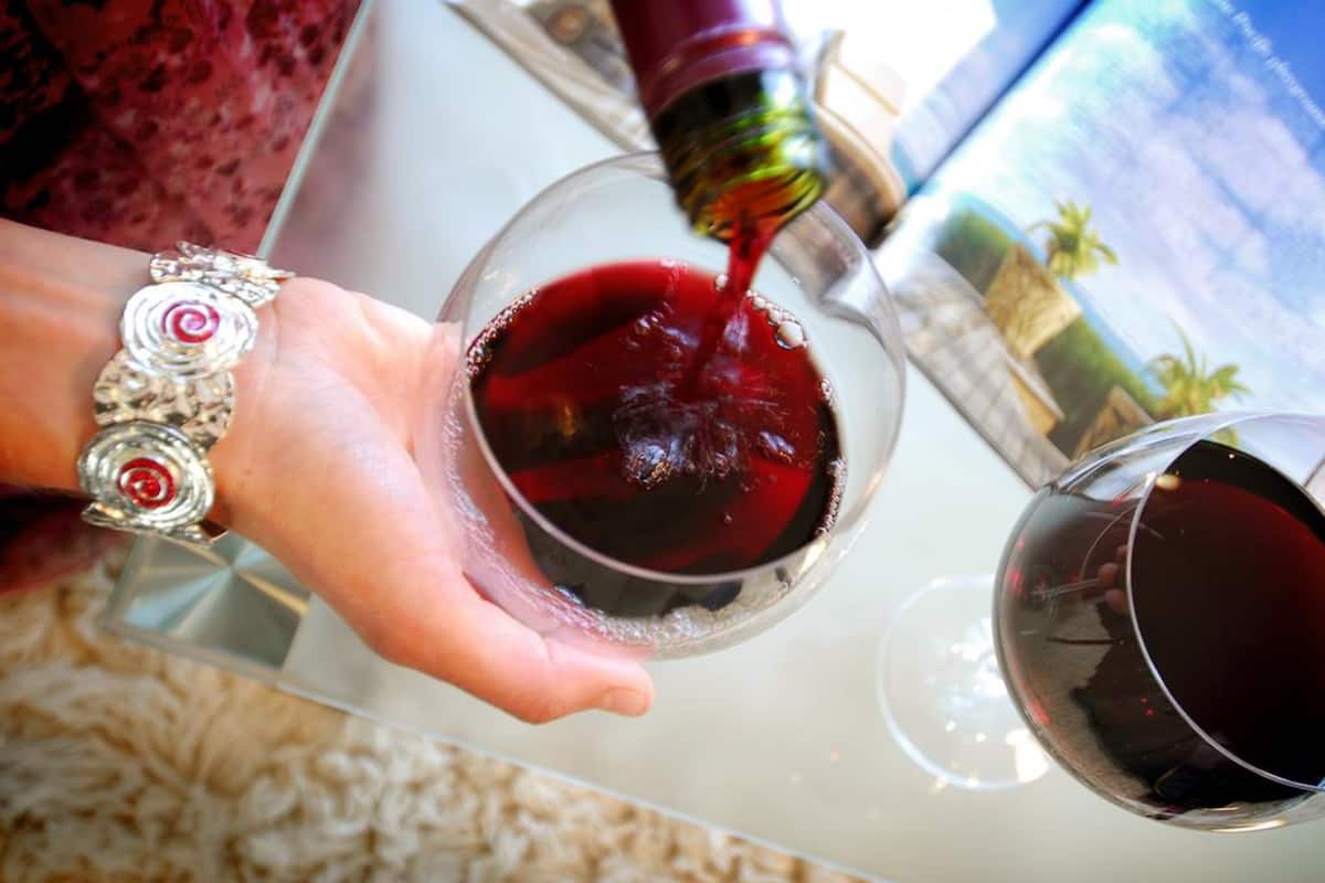 A person pouring red wine into a glass.